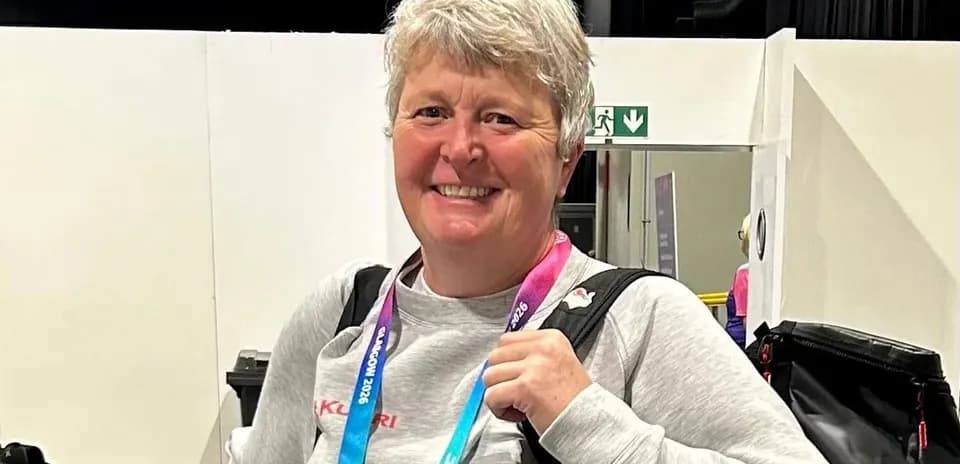 Coach smiling with medal and backpack in venue