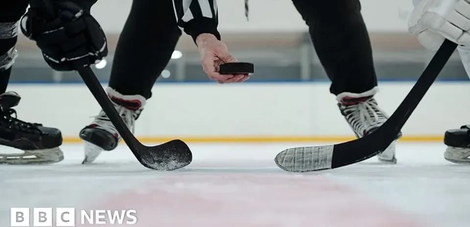 Referee dropping puck for face-off in ice hockey