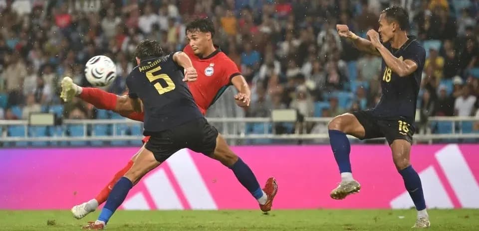 Three players competing for the ball in rain
