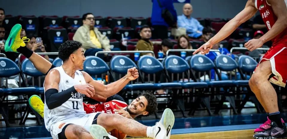 Two basketball players on the court, one falling