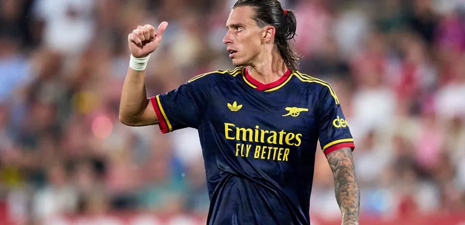 Futbolchi maydonda qo'lini ko'tarib turibdi