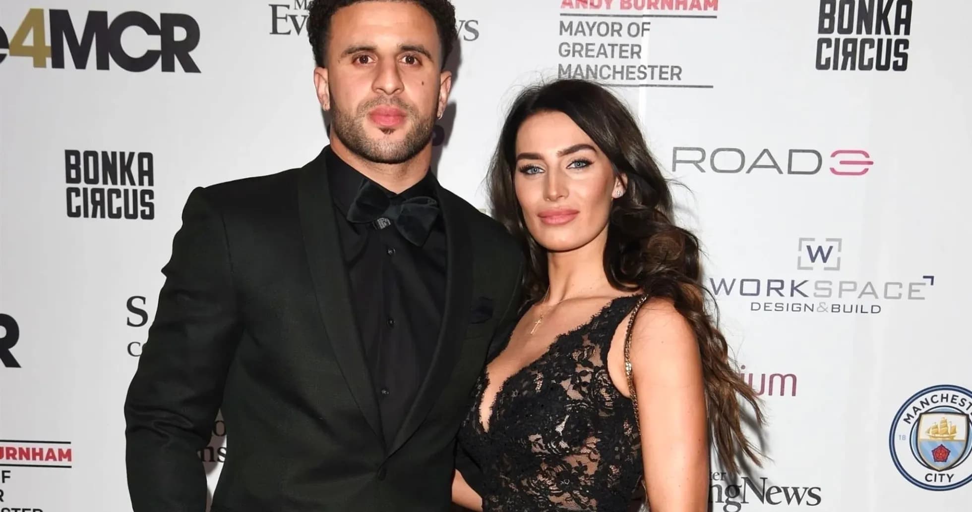 Couple posing at an event with branded backdrop