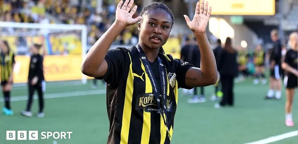 Futbolchi qo'llarini ko'tarib, tomoshabinlarga salom berayotgani