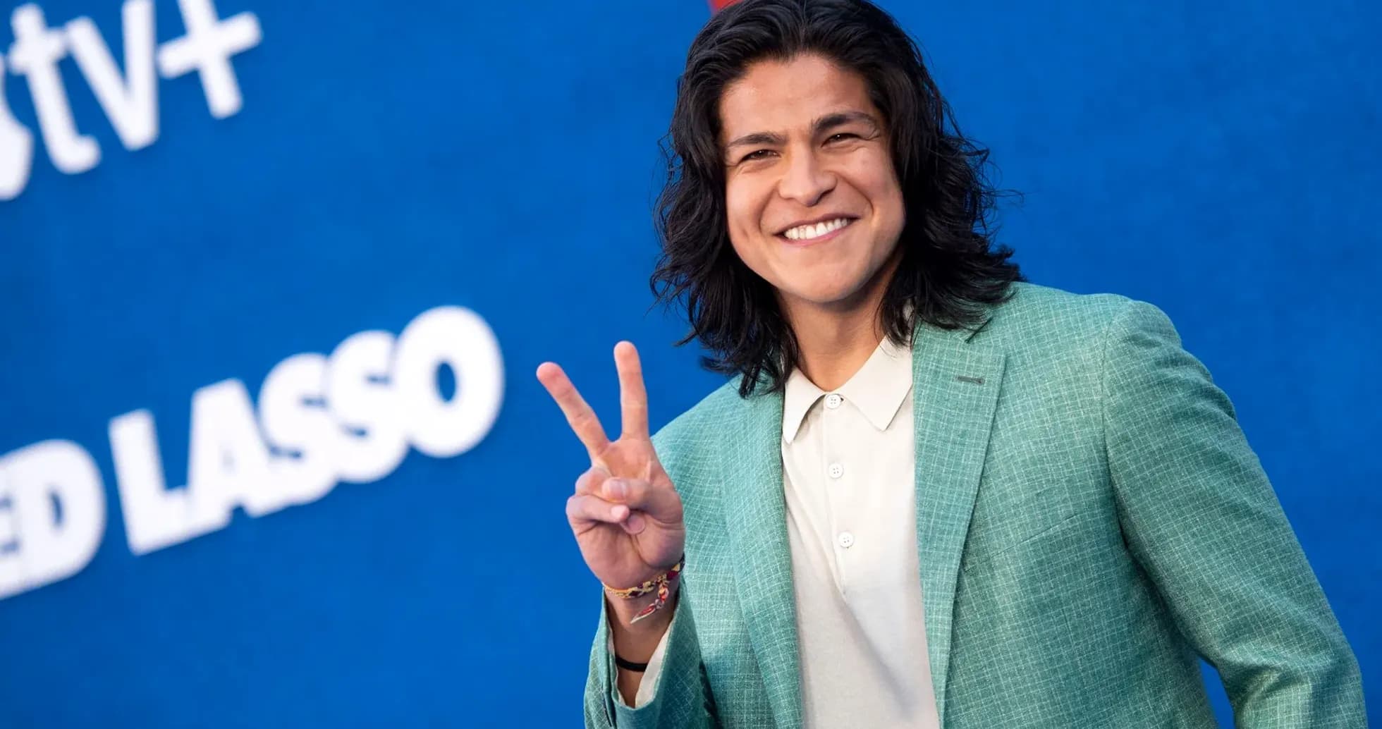 Shirted individual making peace sign at event