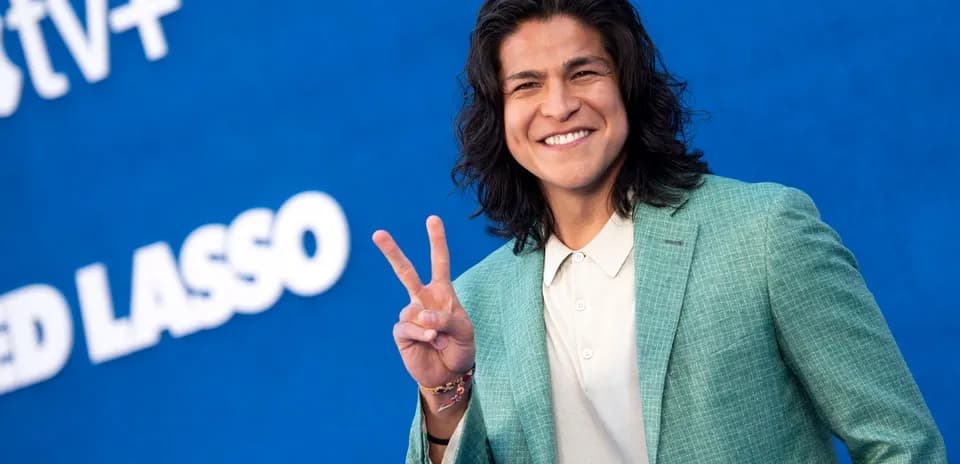 Shirted individual making peace sign at event