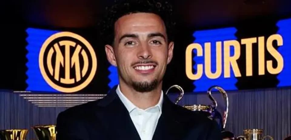 Futbolchi mukofotlar oldida turib kulmoqda