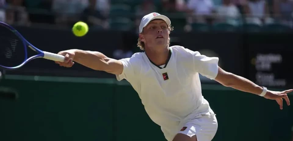 Tennis player reaching for a flying ball