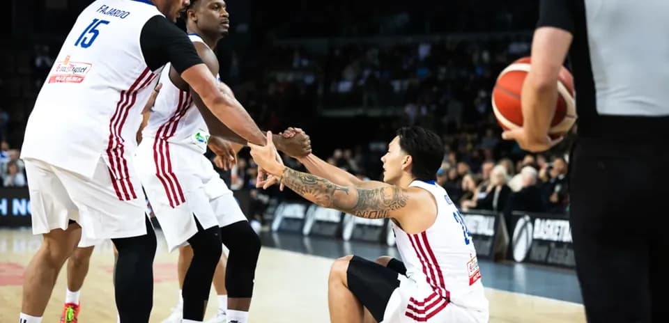 Two players helping teammate up from the court
