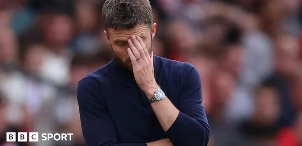 Men's football coach with hand on face during match