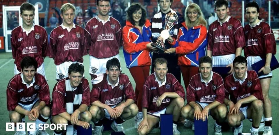 Football team posing with trophy and supporters
