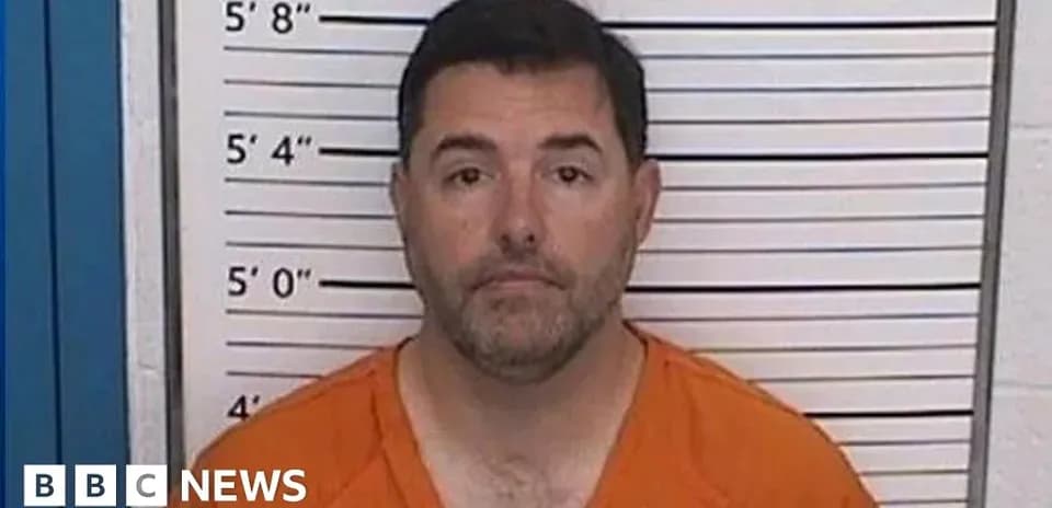 Man in orange jumpsuit at police booking station