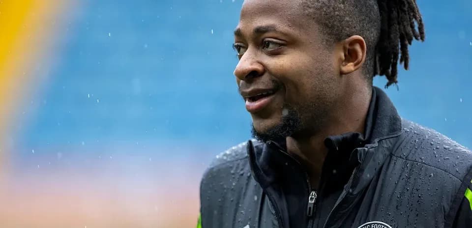 Futbolchi maydonda, yomg'irda kulayotgan holatda
