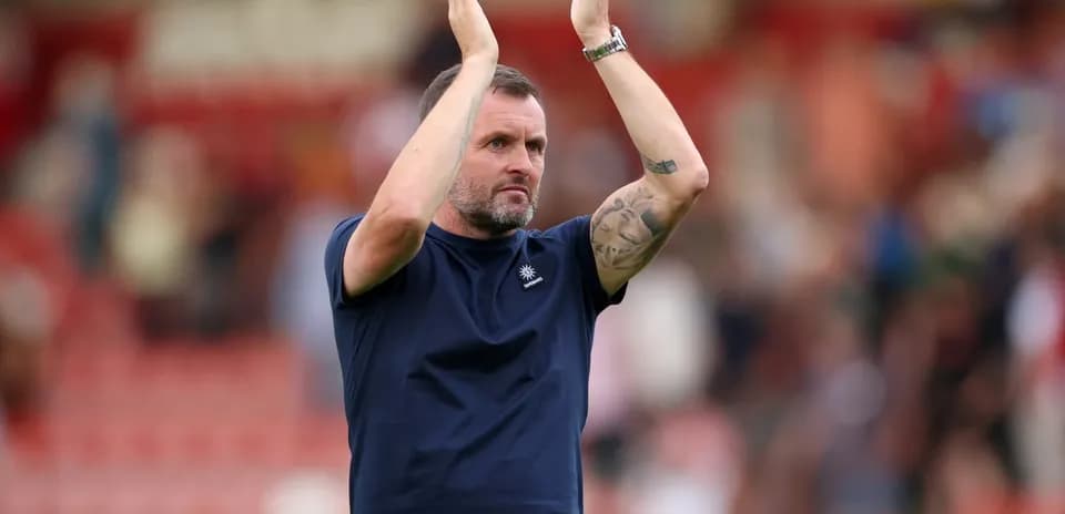 Men's football coach applauding fans after match