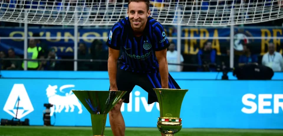 Futbolchi ikki kubok bilan maydonda tabassum qilmoqda