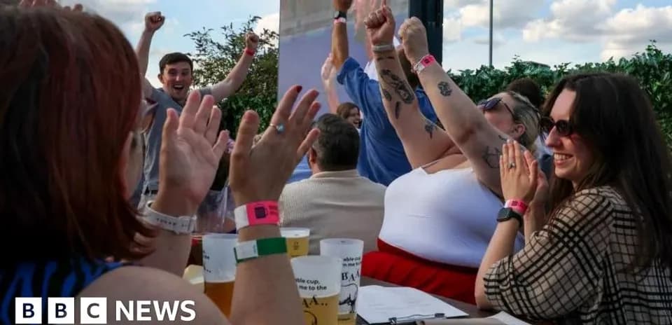 People celebrating with raised hands at outdoor venue