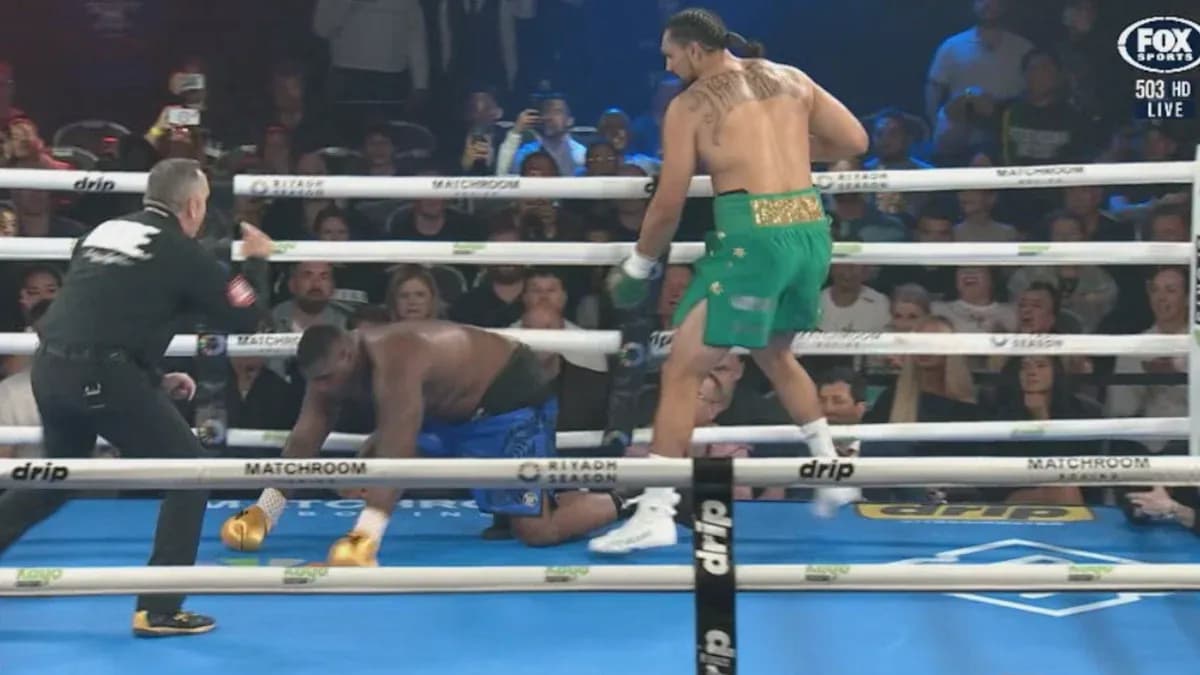Boxer in green celebrating while opponent kneels down