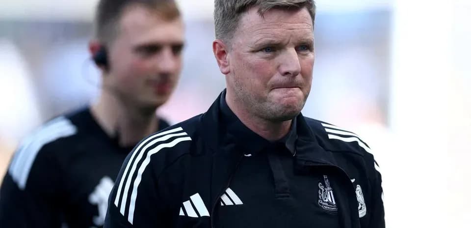 Football manager walking on pitch with staff member