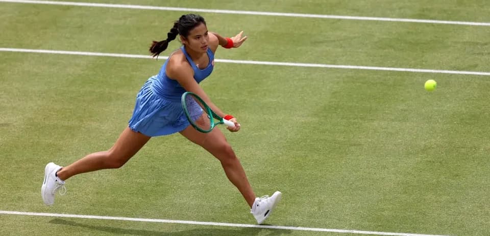 Tennis player reaching for a ball on grass court