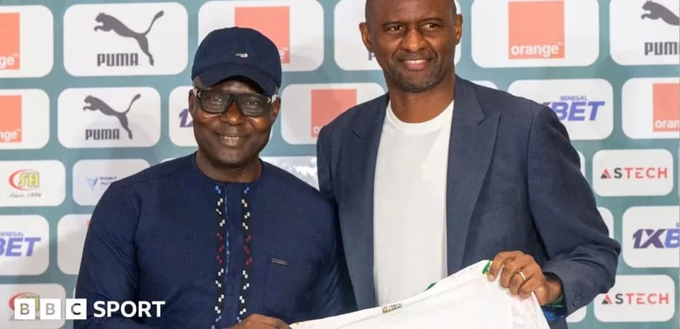 Two men holding a football jersey at a press event