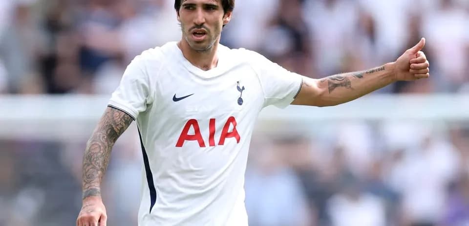 Futbolchi maydonda qo'lini ko'tarib turibdi