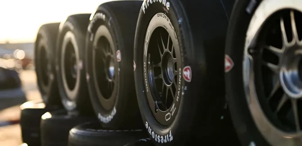 Firestone racing tires stacked in sunlight