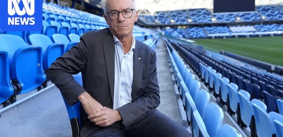 Man seated in empty stadium with blue seats