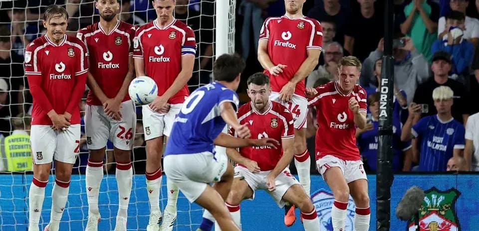 Player taking a free kick in front of wall