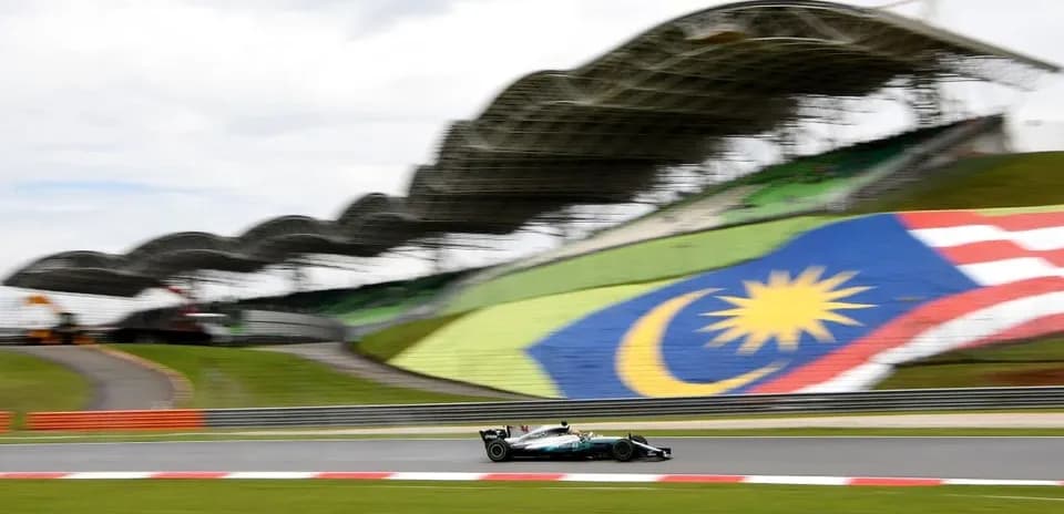 Formula 1 car racing at Malaysian circuit with flag