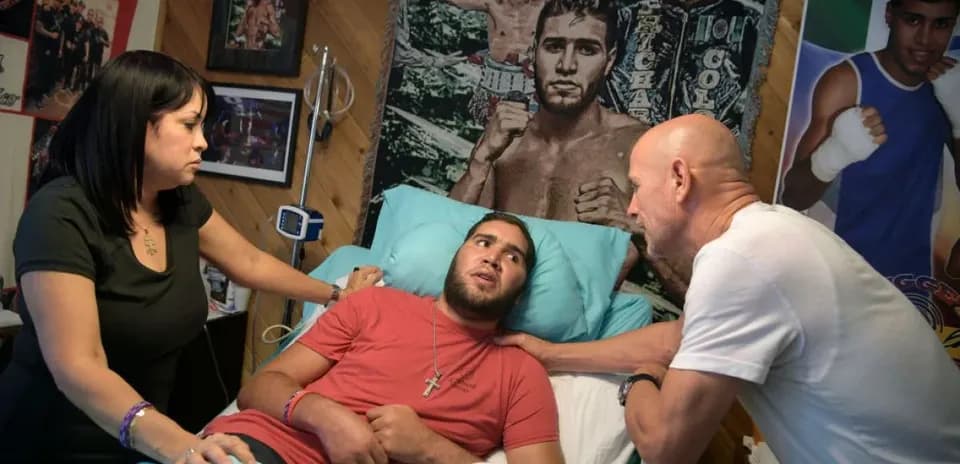 Young man in hospital bed with family members