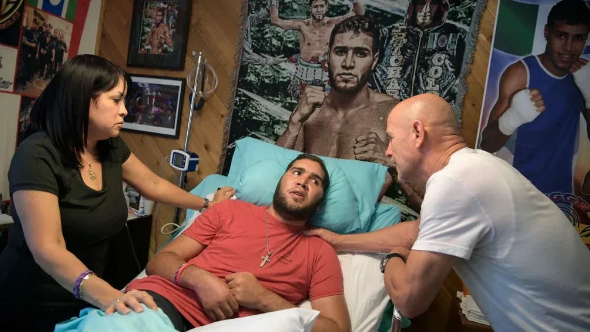 Young man in hospital bed with family members