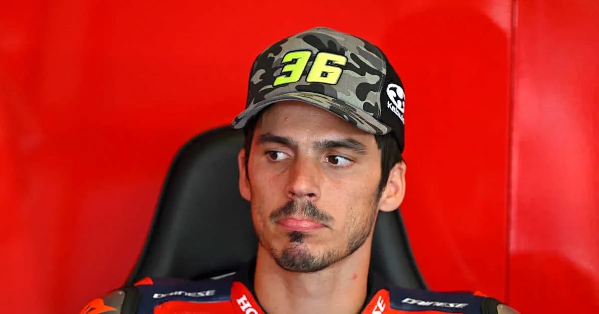MotoGP rider seated with cap in paddock