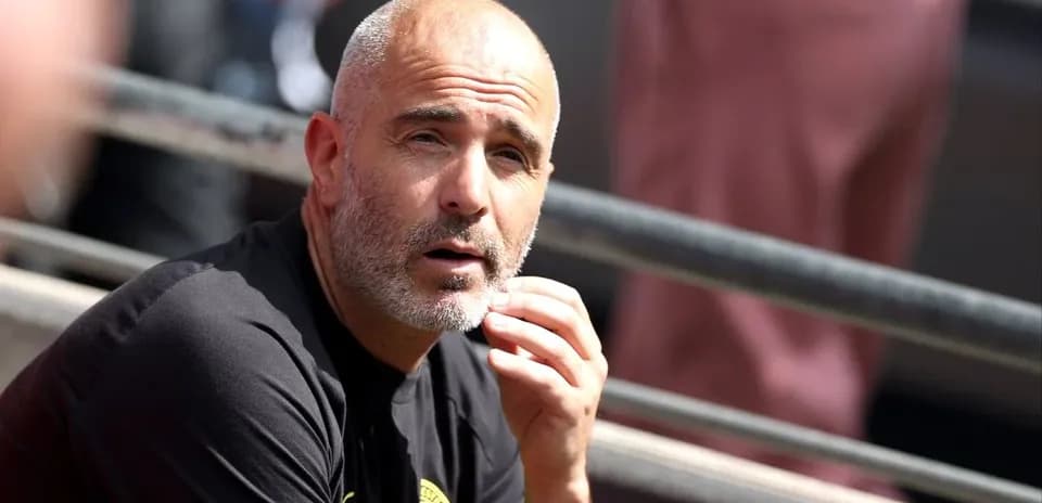 Football manager sitting on bench during match