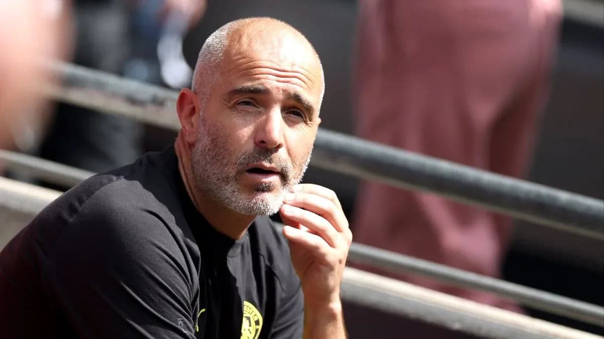 Football manager sitting on bench during match