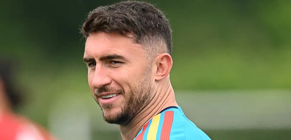 Futbolchi mashg'ulotda, ko'ylakda tabassum qilmoqda