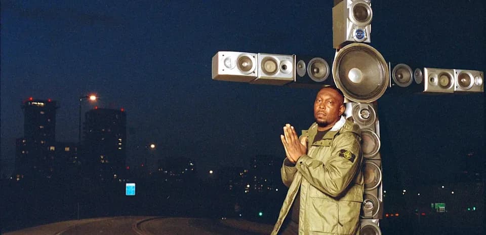 Man posing in front of speaker installation at night