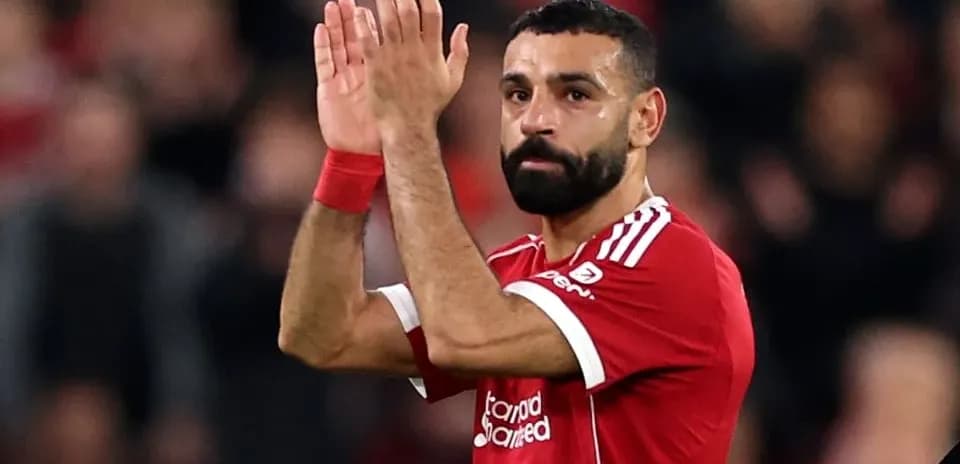 Futbolchi maydonda qo'llarini ko'tarib turgan