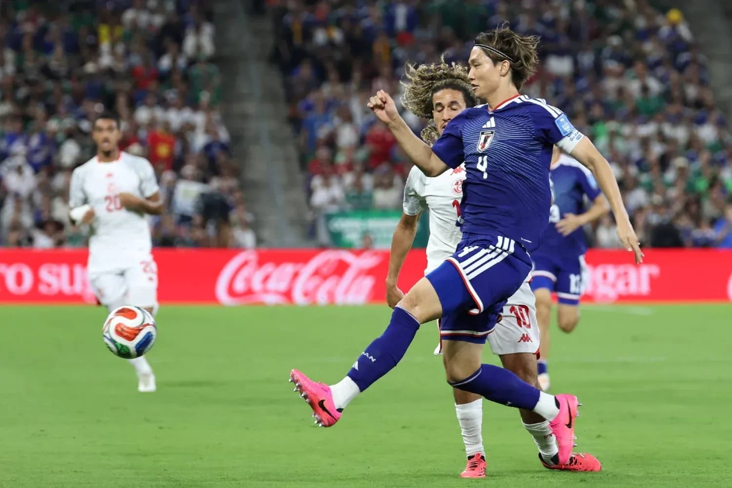 Japan player kicking ball during match against Tunisia