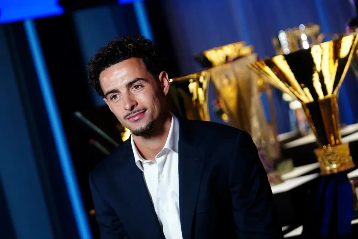 Young man in suit with trophies in background