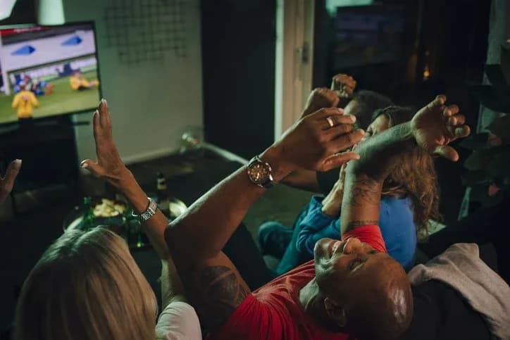 Group celebrating while watching football match on TV