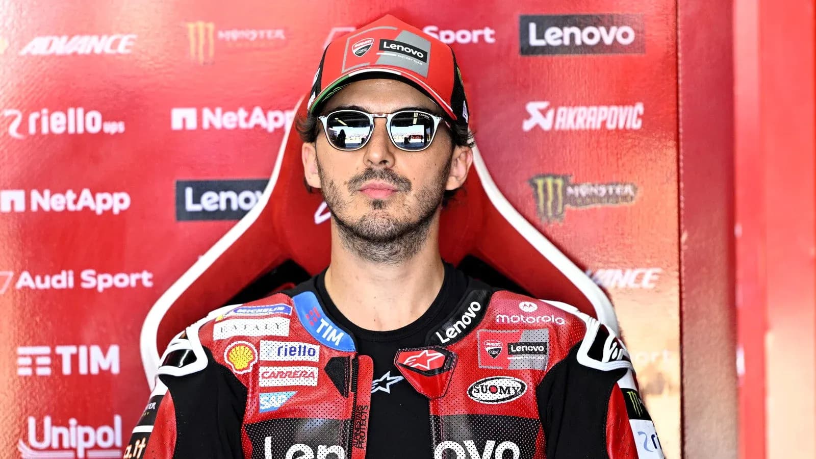 Motorsport athlete sitting in racing gear with sunglasses
