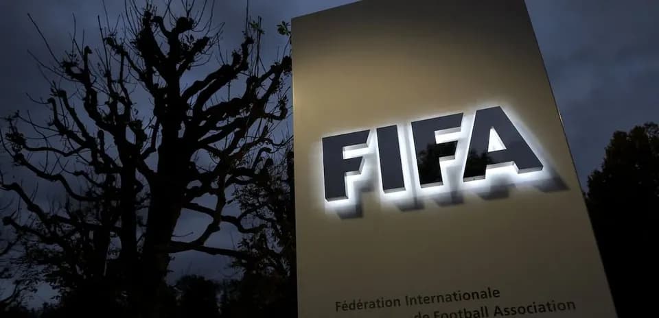 FIFA sign illuminated at dusk with tree background