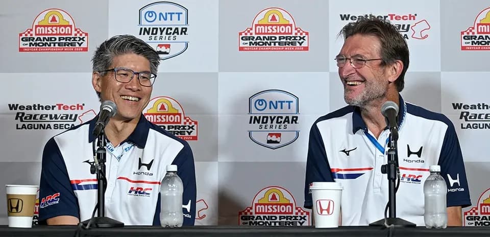 Two men at press conference with Honda branding