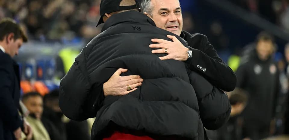 Trainers embracing on the sidelines during match