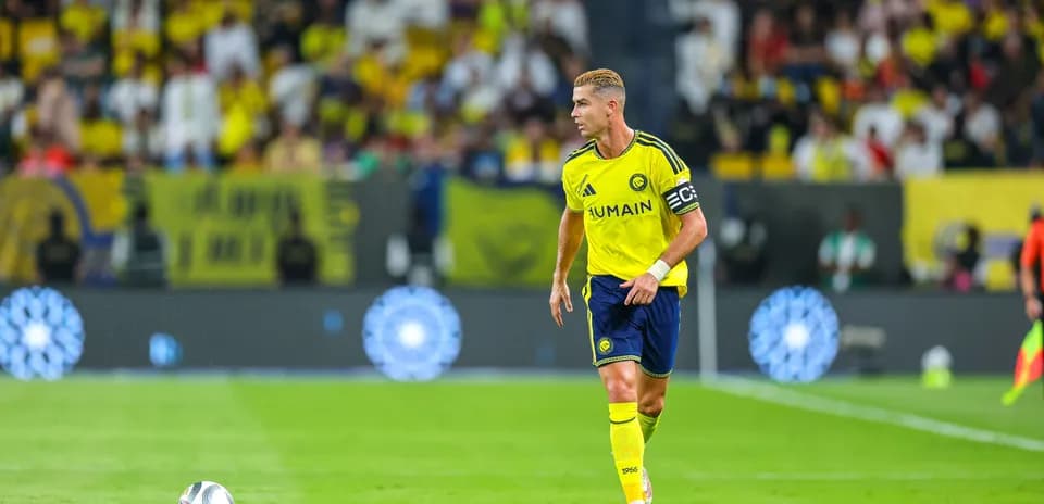 Futbolchi maydonida to'p bilan harakatlanmoqda