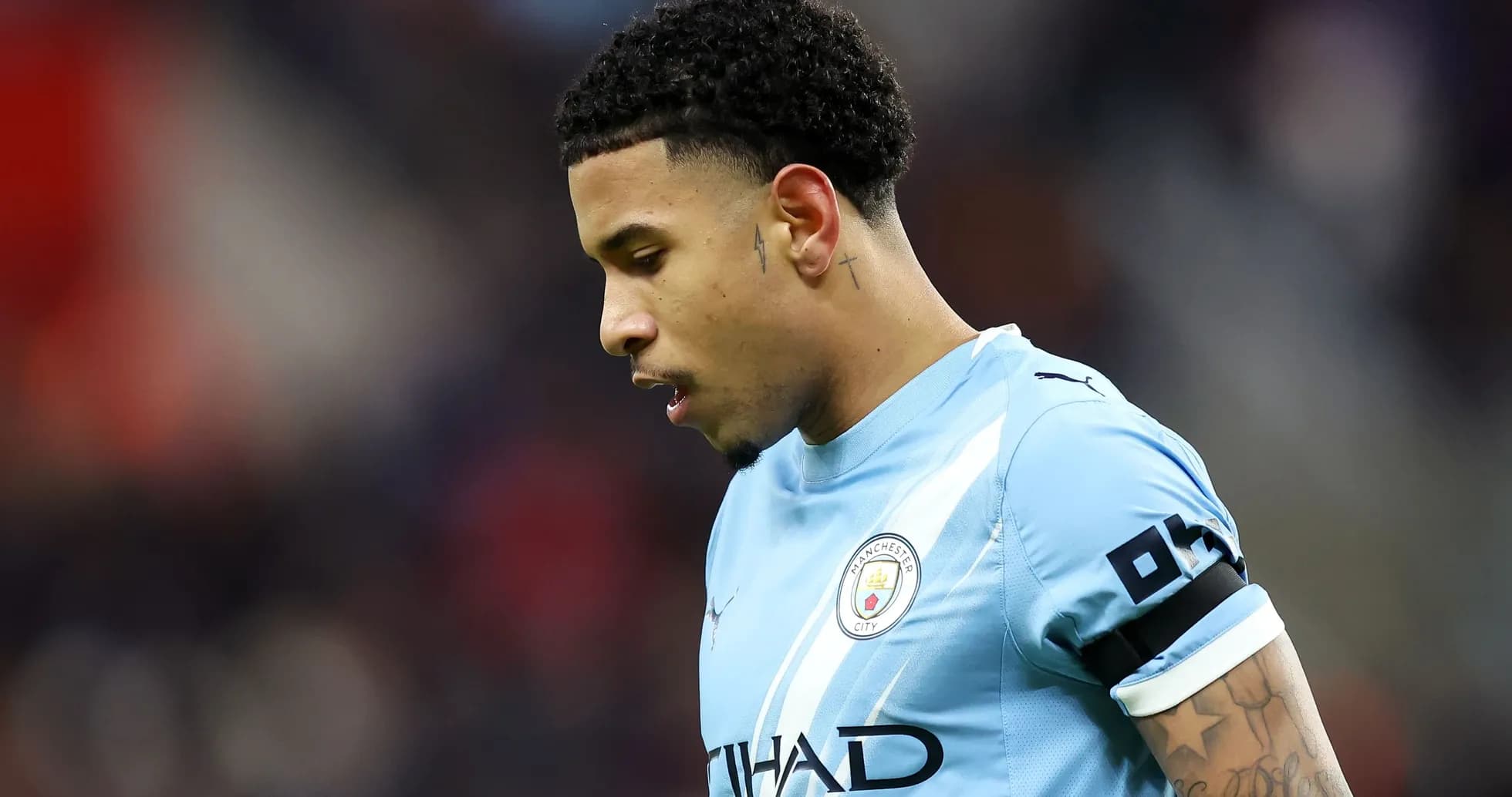 Futbolchi Manchester City formasida, bosh egilgan