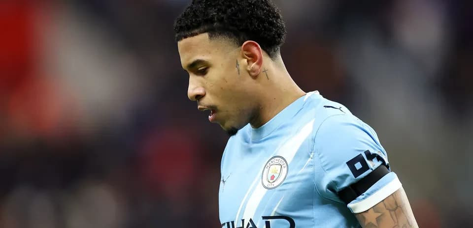 Futbolchi Manchester City formasida, bosh egilgan