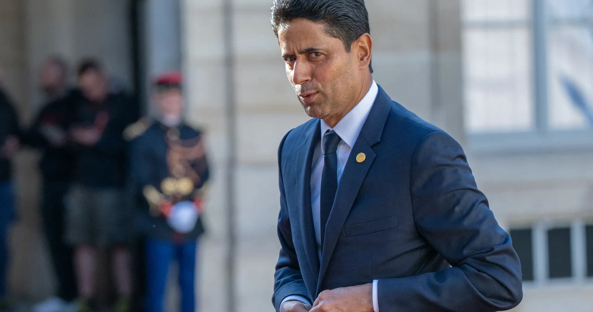Man in suit walking outside near soldiers
