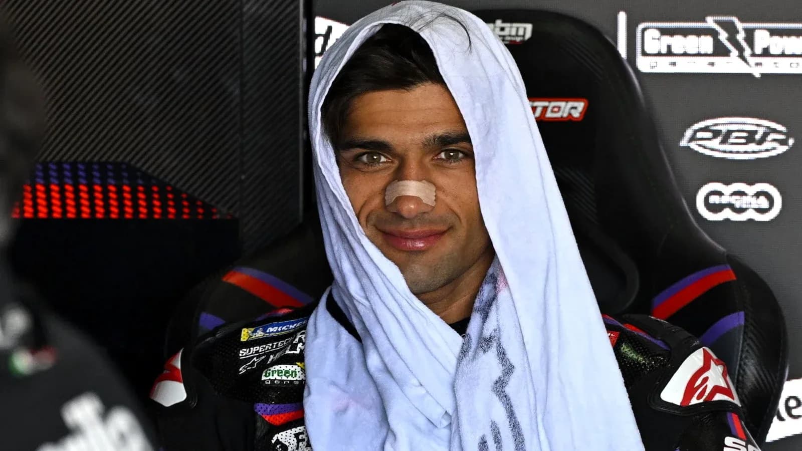 Motorcycle racer with towel and bandage on nose