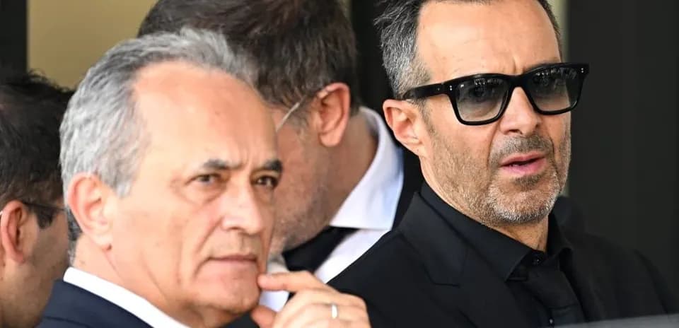 Two men in suits standing outside, wearing sunglasses