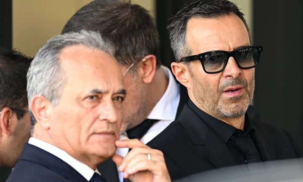 Two men in suits standing outside, wearing sunglasses